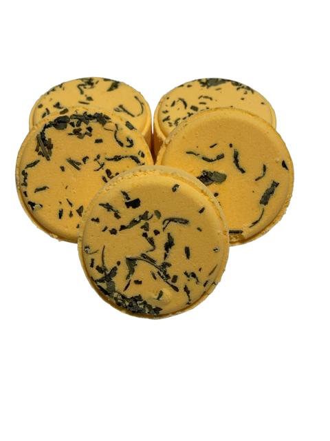 A set of round yellow shower steamers with green tea leaves distributed throughout.